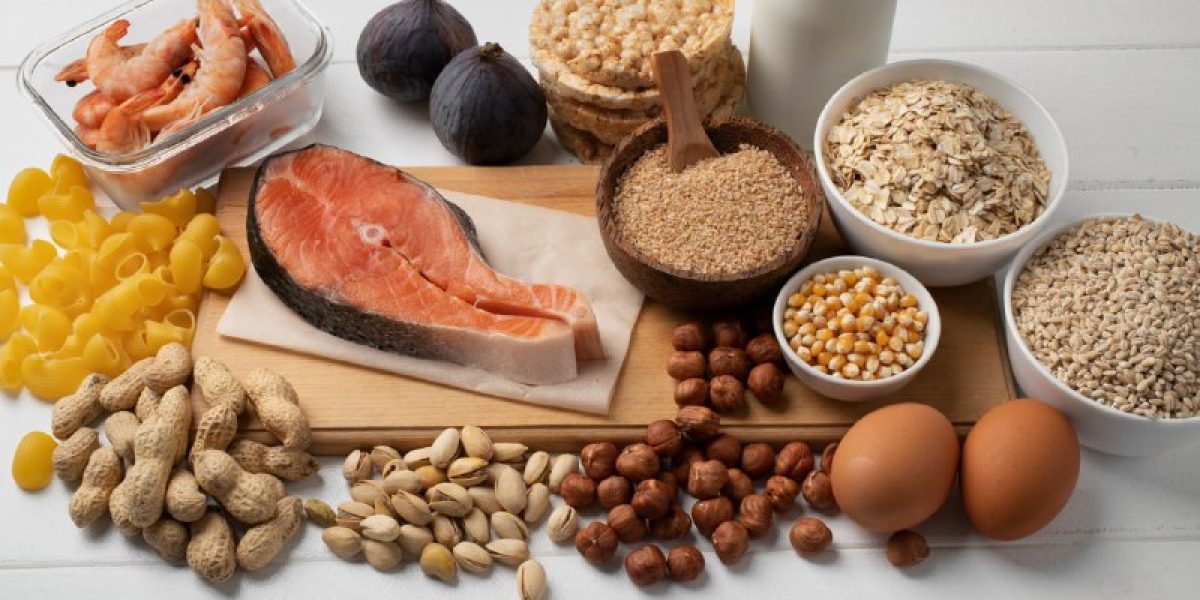 Diversos alimentos que são alérgenos comuns dispostos em uma mesa branca, incluindo amendoim, camarão, ovos, leite, peixe (salmão) e grãos contendo glúten.