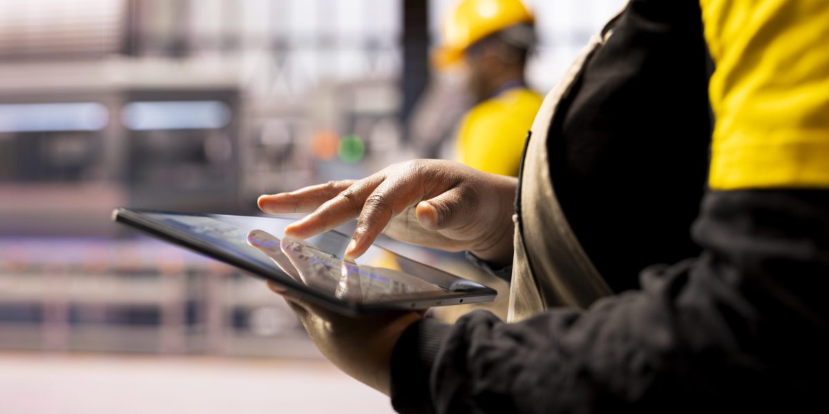 Closeup of professional using tablet in high tech factory, symbolizing industry 4.0, digital automation and real time production monitoring. African american engineer handling robotic arm maintenance.