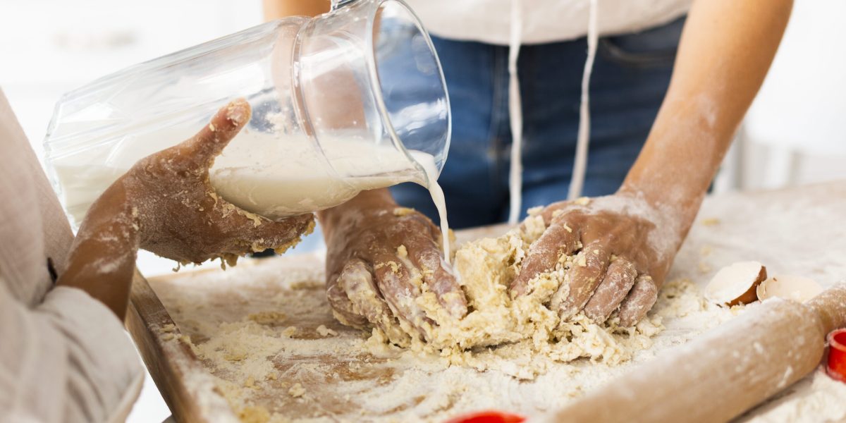 maos-derramando-leite-para-preparar-massa