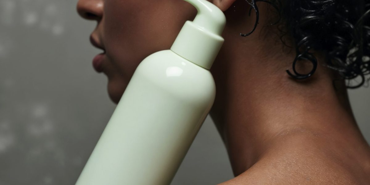 pessoa-com-cabelo-encaracolado-segurando-uma-garrafa-de-produto