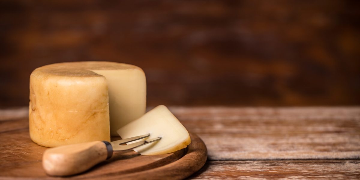 Cheese with fork on wooden board