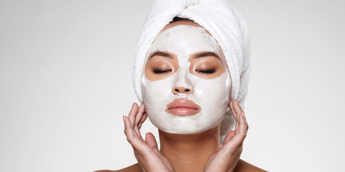 Portrait of beautiful lady with closed eyes and towel on her head put scrab on her face isolated